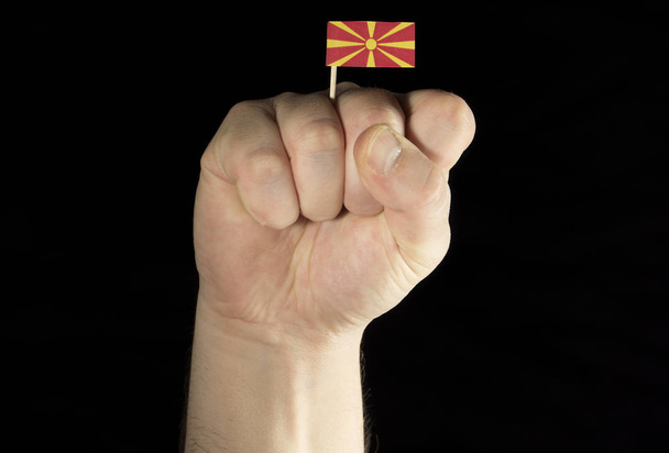 黒い背景に分離されたマケドニアの旗を持つ男の手拳 - 写真・画像