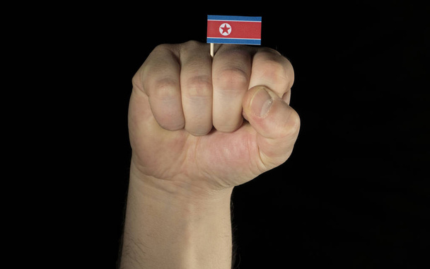 黒背景がある上に分離されて韓国北朝鮮の旗を持つ男の手拳 - 写真・画像