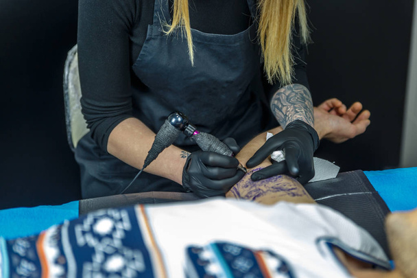 Une tatoueuse dessine avec la machine à tatouer, le contour
  - Photo, image