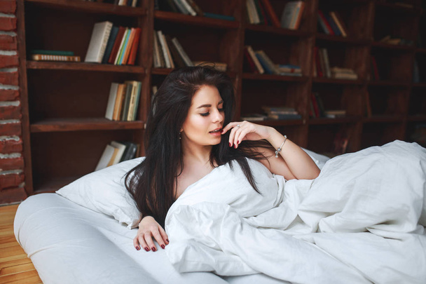 sinnliche Frau mit dunklen Haaren auf einem Bett liegend - Foto, Bild