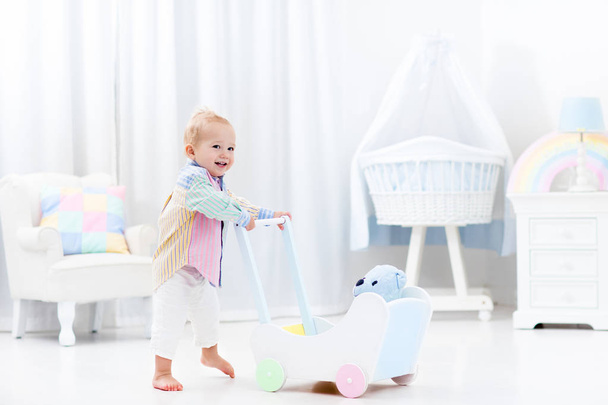 Bebê com caminhante push no quarto branco
 - Foto, Imagem