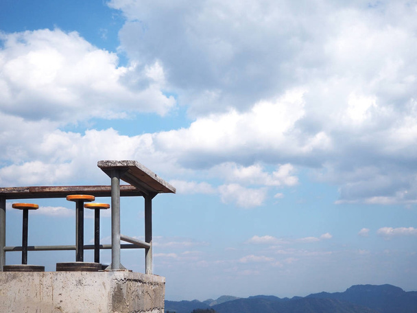 corner of outdoor stools and tables against blue sky with white  - Photo, Image