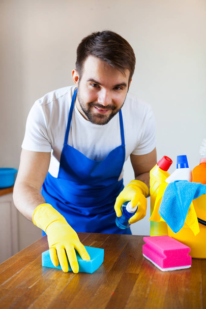 Zbliżenie, młody człowiek ubrany czyszczenia blatem kuchennym fartuch - Zdjęcie, obraz