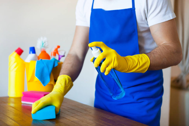 Primo piano di giovane uomo che indossa grembiule pulizia cucina piano di lavoro
 - Foto, immagini