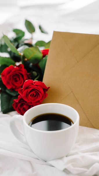 cup of coffee and a bouquet of red roses, envelope - Φωτογραφία, εικόνα