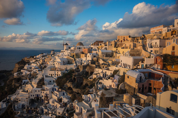 White city on a slope of a hill at sunset, Oia, Santorini, Greec - Photo, image