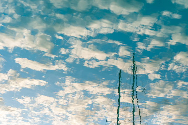 Blu cielo nuvoloso e yacht alberi riflessi in acque calme
  - Foto, immagini