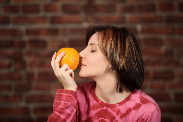 Young woman with orange in hand - Foto, Imagen