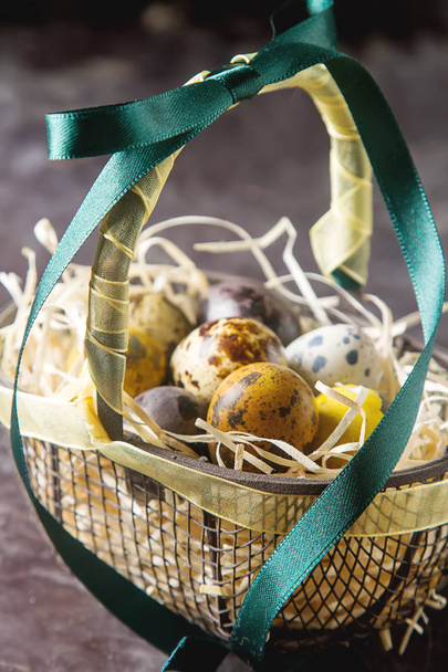 Multi-colored Easter egg. Quail eggs with feathers in basket. Da - Foto, imagen
