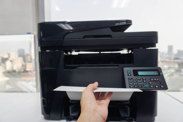 liikenainen tuoda painettuja asiakirjoja toimistosta tulostimen vasemmalla kädellä
 - Valokuva, kuva