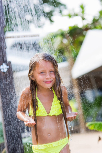 Pretty smiling girl standing under the spray of water in the shower on the beach - Foto, Bild