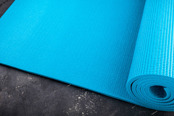 Yoga mat op donkere achtergrond. Uitrusting voor yoga. Concept gezonde levensstijl, sport en voeding. Kopiëren van ruimte - Foto, afbeelding