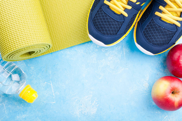 Yoga mat, spor ayakkabı, elma, şişe su koyu arka plan üzerinde. Kavram sağlıklı yaşam tarzı, sağlıklı gıda, spor ve diyet. Spor donatımı - Fotoğraf, Görsel
