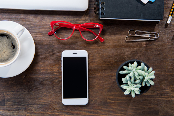 Coffee cup and smartphone on desk - Фото, изображение