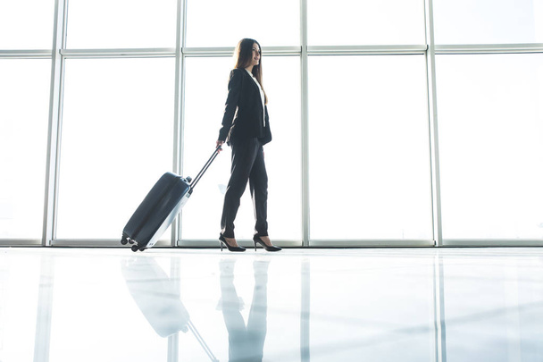 空港内を歩いて荷物バッグを持つ女性実業家 - 写真・画像