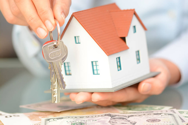 Buying a house concept with woman hands holding a model house and keys - Photo, Image