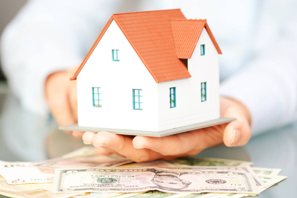Buying a house concept with woman hands holding a model house  - Photo, Image