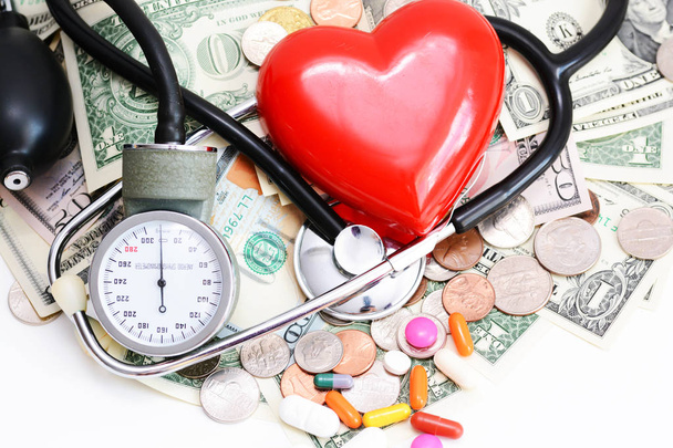 Ziektekostenverzekering concept met rood hart, pillen en medische instrumenten op stapel geld - Foto, afbeelding
