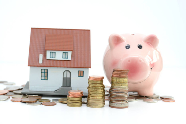 Piggy bank en model huis op cash suggereren besparingen voor huis - Foto, afbeelding