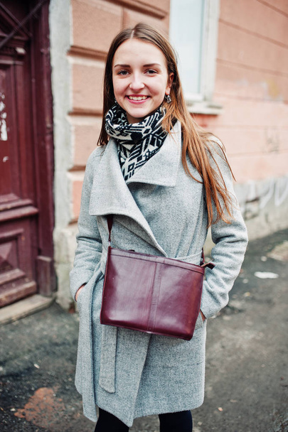 Young model girl in a gray coat with leather handbag on shoulder - Φωτογραφία, εικόνα