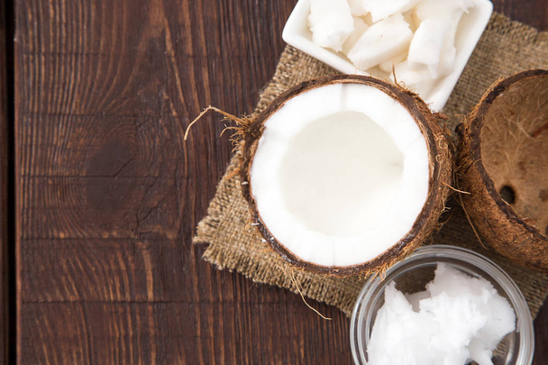 Coconut with coconut oil in jar on wooden background - Photo, Image