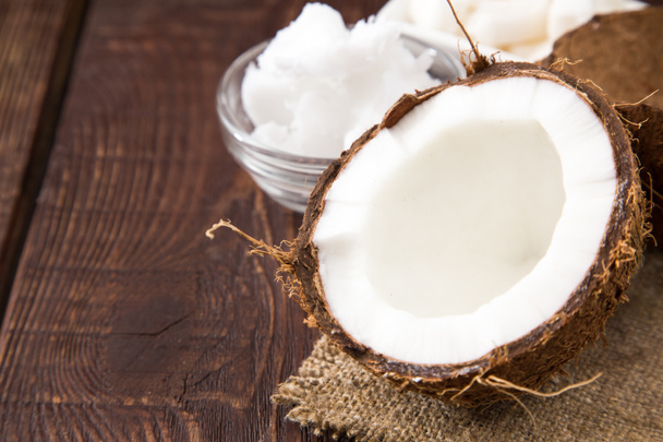Coconut with coconut oil in jar on wooden background - Photo, Image