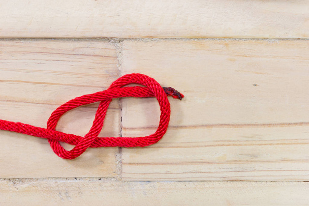 Figure-huit noeud en corde rouge sur fond en bois
 - Photo, image