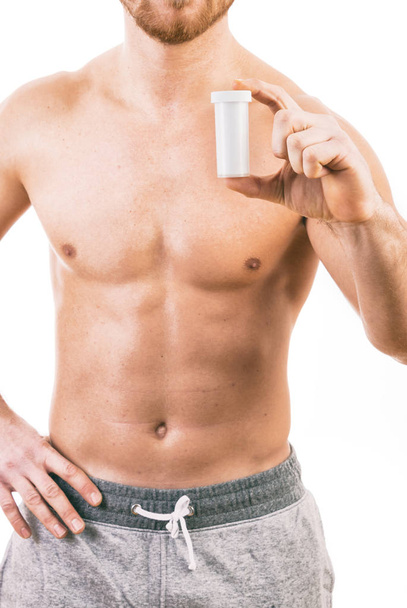 Muscoloso giovane uomo in possesso di una bottiglia di pillole isolato
  - Foto, immagini