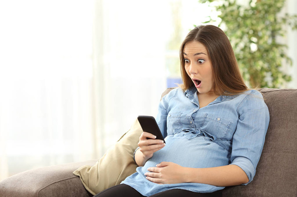 Amazed pregnant woman looking at smart phone - Fotoğraf, Görsel
