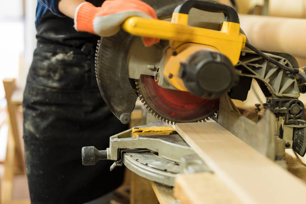 Closeup of woman cutting piece of wood  - Fotografie, Obrázek