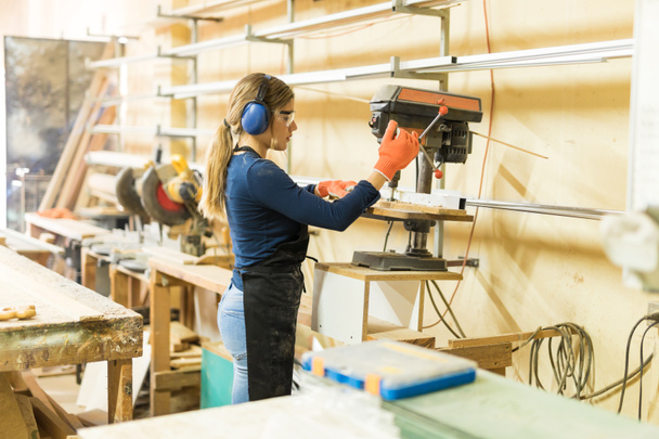 woman carpenter using drill press - 写真・画像