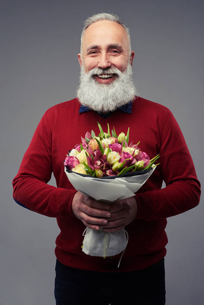Senior bearded man holding a bouquet of tulips - Foto, afbeelding
