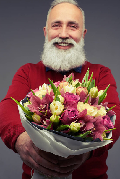 Smiling bearded man holding a big bouquet of spring tulips  - Fotó, kép