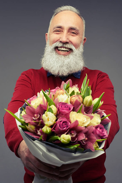Fröhlicher bärtiger Senior überreicht einen Strauß Tulpen - Foto, Bild