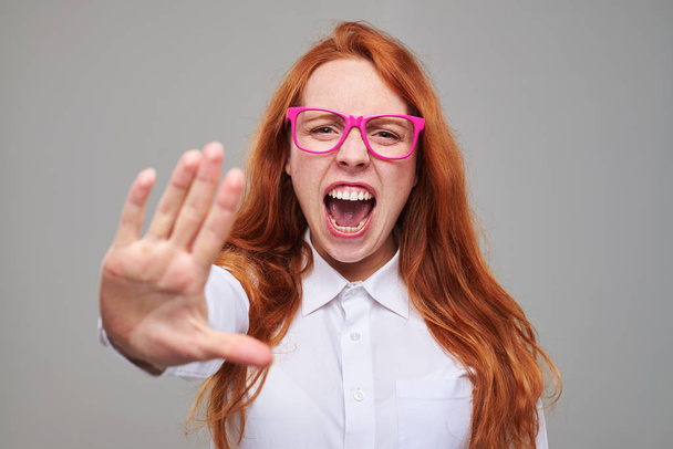  Gritando furioso pelo rojo chica muestra señal de stop por su mano
 - Foto, Imagen