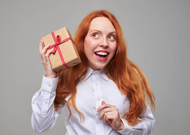 Curious girl shaking a present box - Foto, imagen