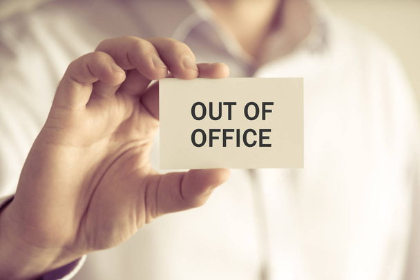 Empresário segurando OUT OF OFFICE cartão de mensagem
 - Foto, Imagem