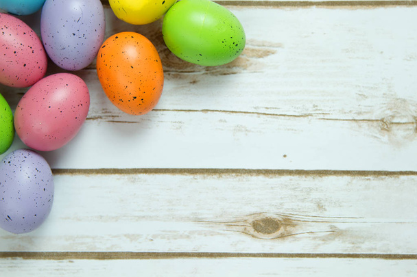 Huevos de Pascua salpicados sobre una tabla de madera fondo de tablero encalado
 - Foto, imagen