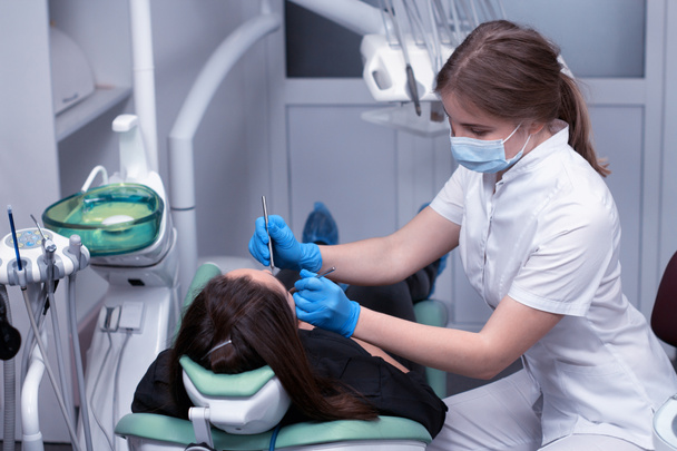 Dişçi kadının diş inceleyerek iş başında - Fotoğraf, Görsel