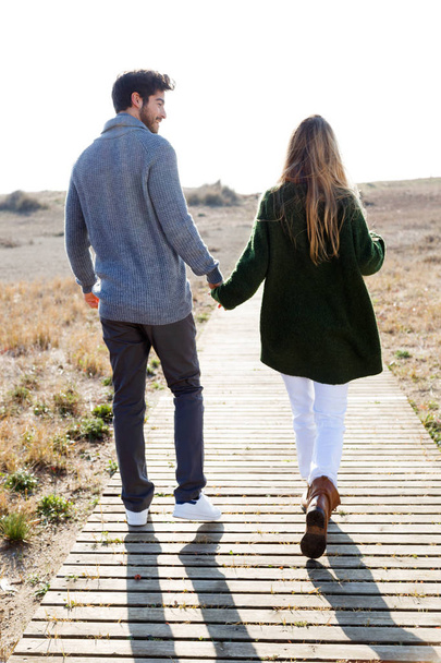 schönes junges verliebtes Paar geht in einem kalten Winter am Strand spazieren. - Foto, Bild