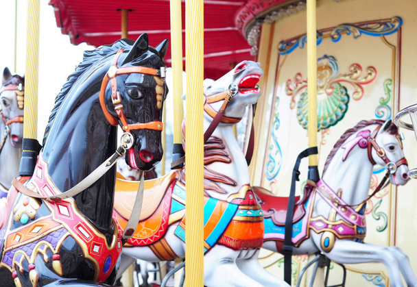Hermoso carrusel de caballos en un parque de vacaciones. Tres caballos en un carrusel tradicional de feria
.  - Foto, imagen