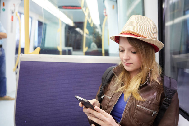 Smiling girl using smartphone in subway train at metro - Foto, afbeelding