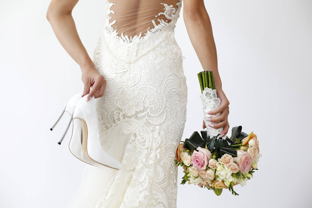 Gorgeous bride with shoes and bouquet on isolated background - Photo, Image