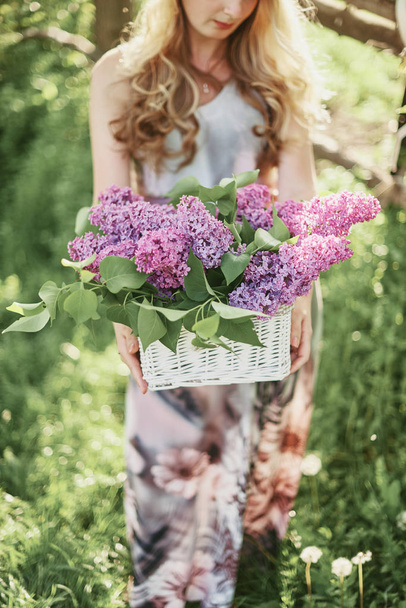 Meisje met mand van bloemen op de achtergrond van de natuur - Foto, afbeelding