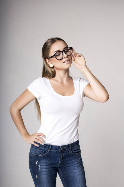 Modern woman in blank white t-shirt over gray background - 写真・画像