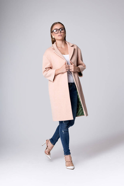 Modern model in a pink coat in the studio - Foto, Bild