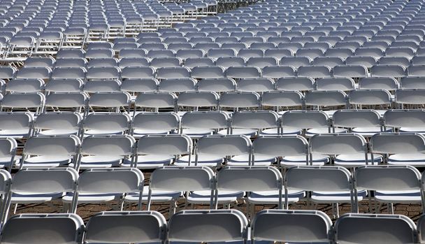 Paljon valkoisia tuoleja stadionilla
 - Valokuva, kuva