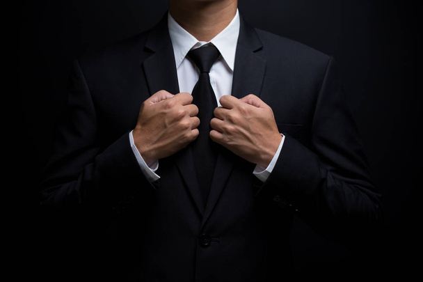 Homme en costume noir et ajustant sa cravate
 - Photo, image