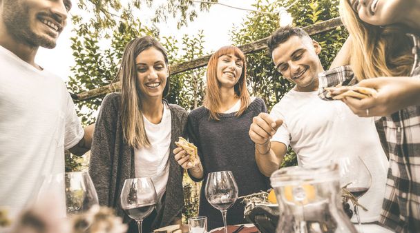 Happy vrienden plezier drinken van rode wijn, eten bij tuinfeest - vriendschap concept samen bij boerderij wijngaard winery - Focus op meisje in het midden met retro desaturated ondoorzichtige contrast filter - Foto, afbeelding