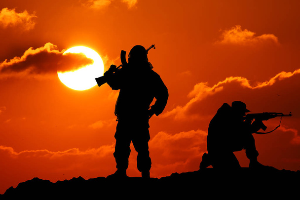 Két férfi agyonlőtték, egy katona fegyvert és Vit hegyi piktureskie bakkdrop al naplemente - Fotó, kép